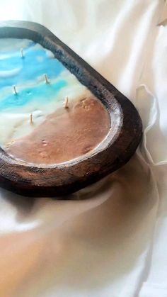 a wooden tray with some blue and white paint in it on top of a bed