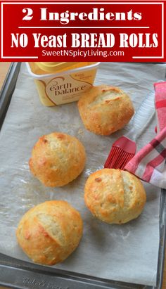 three bread rolls sitting on top of a baking sheet next to a container of butter