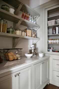 a kitchen with white cabinets and shelves filled with food