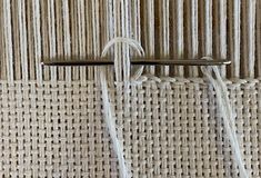 two knitting needles are hooked up to the side of a piece of woven material that has been stitched together