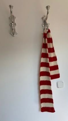 a red and white striped towel hanging from a hook on a wall next to a light switch