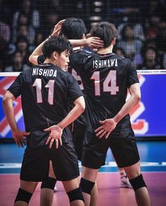 three men in black uniforms standing on a volleyball court with their arms around each other