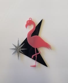 a pink flamingo standing on top of a black triangle with a star in the middle