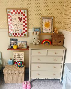 there is a dresser and toy chest in the room with two pictures on the wall