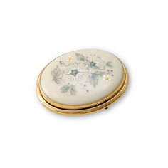 an oval shaped box with flowers painted on the side and gold trimming around it