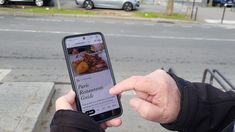 a person holding up a cell phone in front of a street