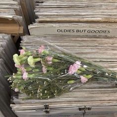 some flowers are laying on top of old books in a store display case that says oldes but goodies