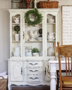 a white china cabinet with wreaths on top