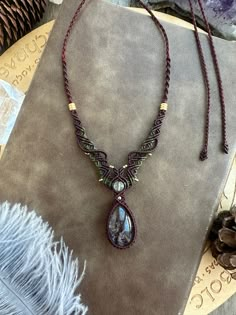 a necklace is displayed on a table next to some feathers and other jewelry items in the background