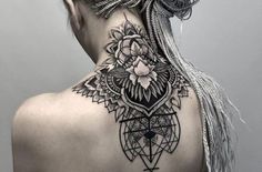 the back of a woman's neck with an intricate tattoo design on her left shoulder