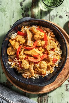 a bowl filled with chicken and rice on top of a wooden table