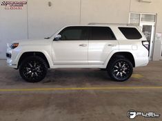 a white suv parked in front of a building with black wheels and rims on it