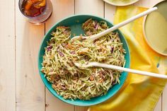 a bowl filled with coleslaw slaw next to two cups and spoons