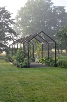 a small metal structure sitting in the middle of a lush green field