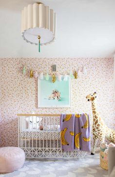 a baby's room with a giraffe, crib and wallpaper