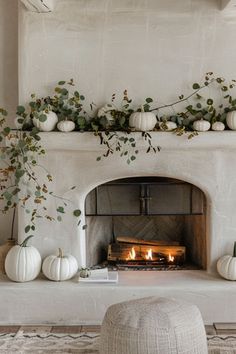 the fireplace is decorated with white pumpkins and greenery