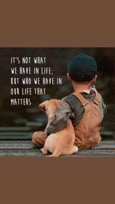 a little boy sitting on top of a wooden floor next to a brown dog wearing a hat