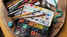 an assortment of art supplies sitting on top of a wooden table next to each other