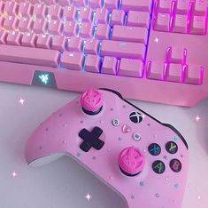 a pink gaming controller sitting next to a keyboard