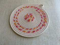 a white rug with multicolored braiding on top of the floor next to a pillow