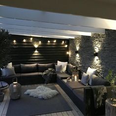 a living room filled with lots of furniture next to a stone wall covered in lights