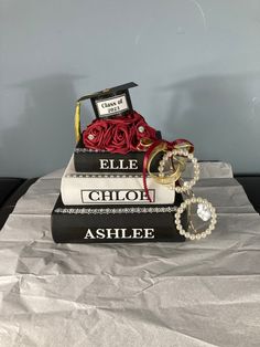 two books stacked on top of each other with graduation caps and rings attached to them