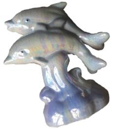 three ceramic dolphins sitting on top of each other in front of a white background,