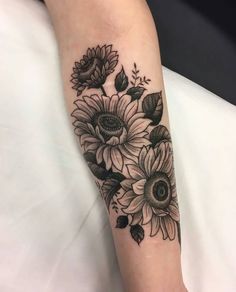 a woman's arm with sunflowers and leaves tattoo on the left forearm