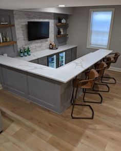 a kitchen with an island and bar stools in front of the counter top that has bottles on it