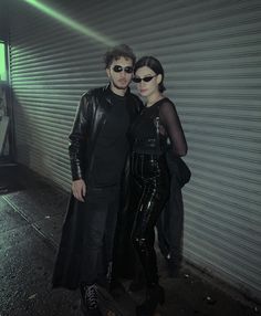 a man and woman standing next to each other in front of a building with shutters