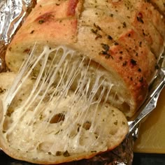 a piece of bread that is covered in melted cheese and other toppings, sitting on tin foil