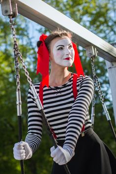 a woman with clown makeup on holding onto a swing