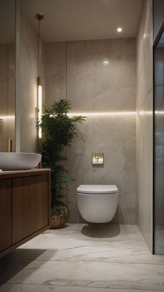 a white toilet sitting next to a sink in a bathroom under a light on the wall