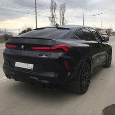 the rear end of a black bmw x4 parked in front of a gas station