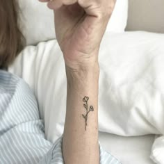 a woman's arm with a small flower tattoo on it