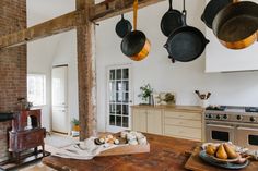 an old fashioned kitchen with pots and pans hanging from the ceiling