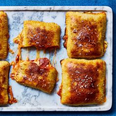 four square pastries on a baking sheet covered in melted cheese and tomato sauce,