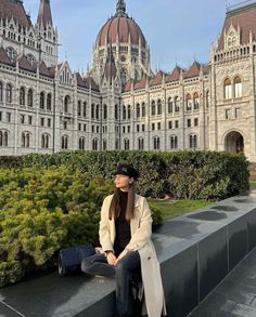 a woman sitting on top of a cement bench in front of a castle like building