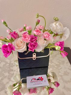 a black box with pink and white flowers in it sitting on a table next to a card