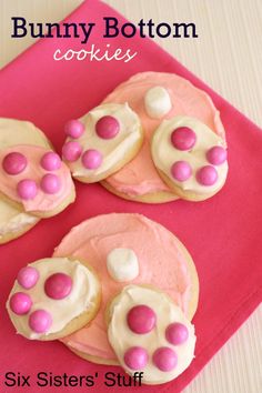 three cookies with pink and white icing are on a red plate