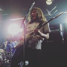 a man with long hair playing guitar in front of microphones and other musical instruments