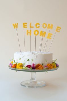 a welcome home cake with flowers and sticks sticking out of the frosting on top