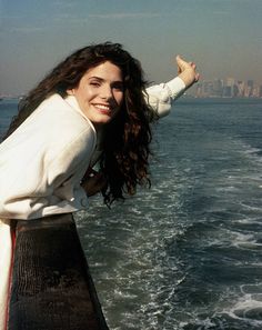 a woman standing on the back of a boat in the ocean with her arms outstretched