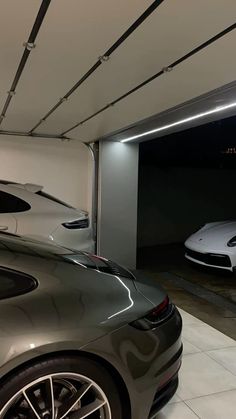 two porsches are parked in a garage with their lights on and the doors open