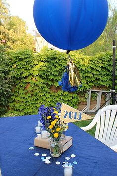 a blue table topped with a vase filled with flowers next to a blue and white balloon