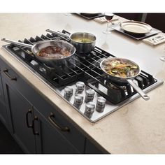 two pots and pans are cooking on the stove top, with utensils