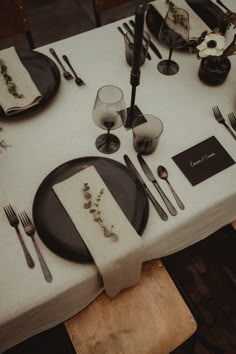 the table is set with black plates and silverware, napkins and place settings