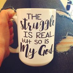 a person holding a coffee mug with the words, the struggle is real but so is my god