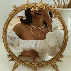 a woman taking a selfie in front of a gold framed mirror on a table