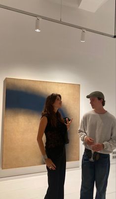 a man and woman standing in front of a painting